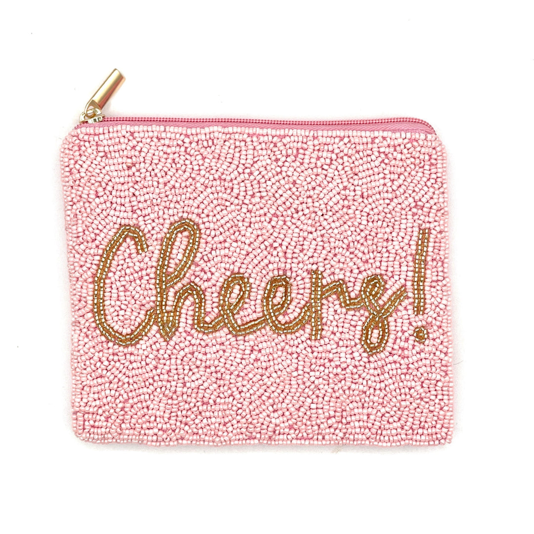A pink beaded coin purse with the word 'CHEERS' written in gold letters.