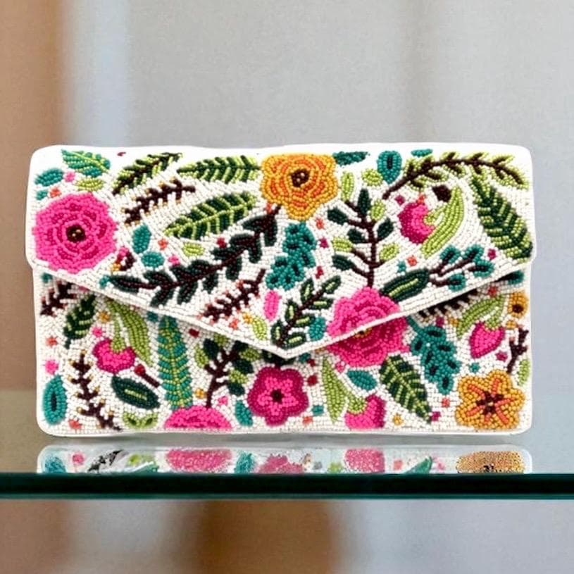 Floral embroidered clutch bag on a reflective surface with a blurred background