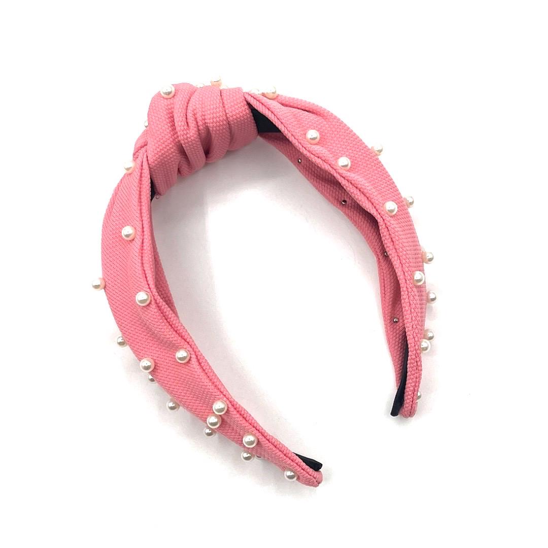 Pink headband with pearl embellishments on a white background