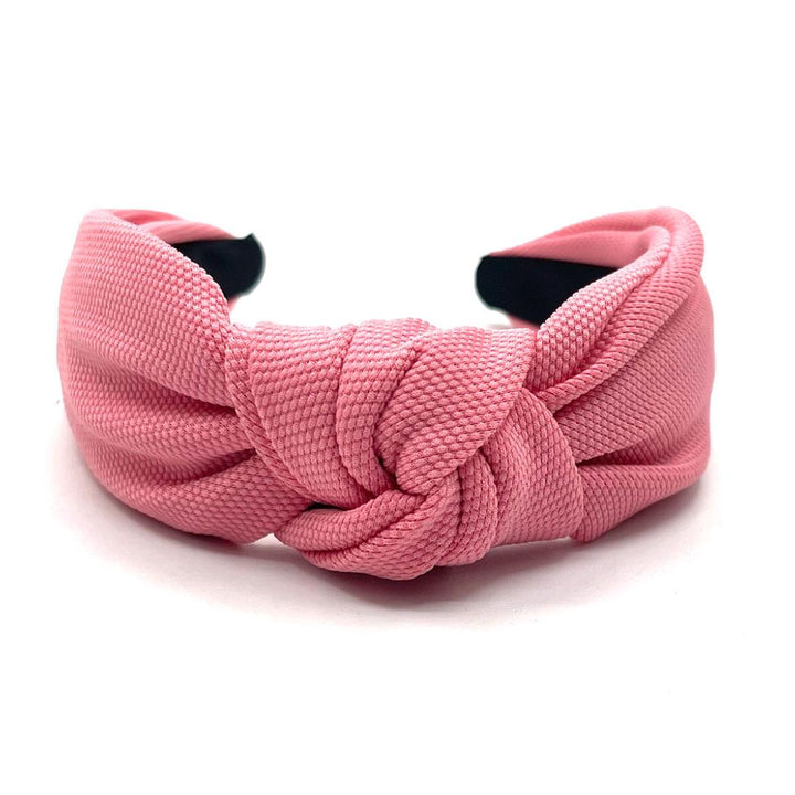Pink knotted headband on a white background