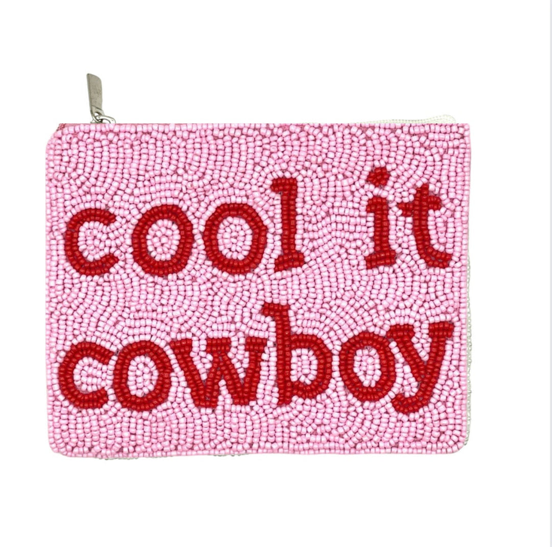 A pink beaded coin purse with the text 'COOL IT COWBOY' embroidered in red.