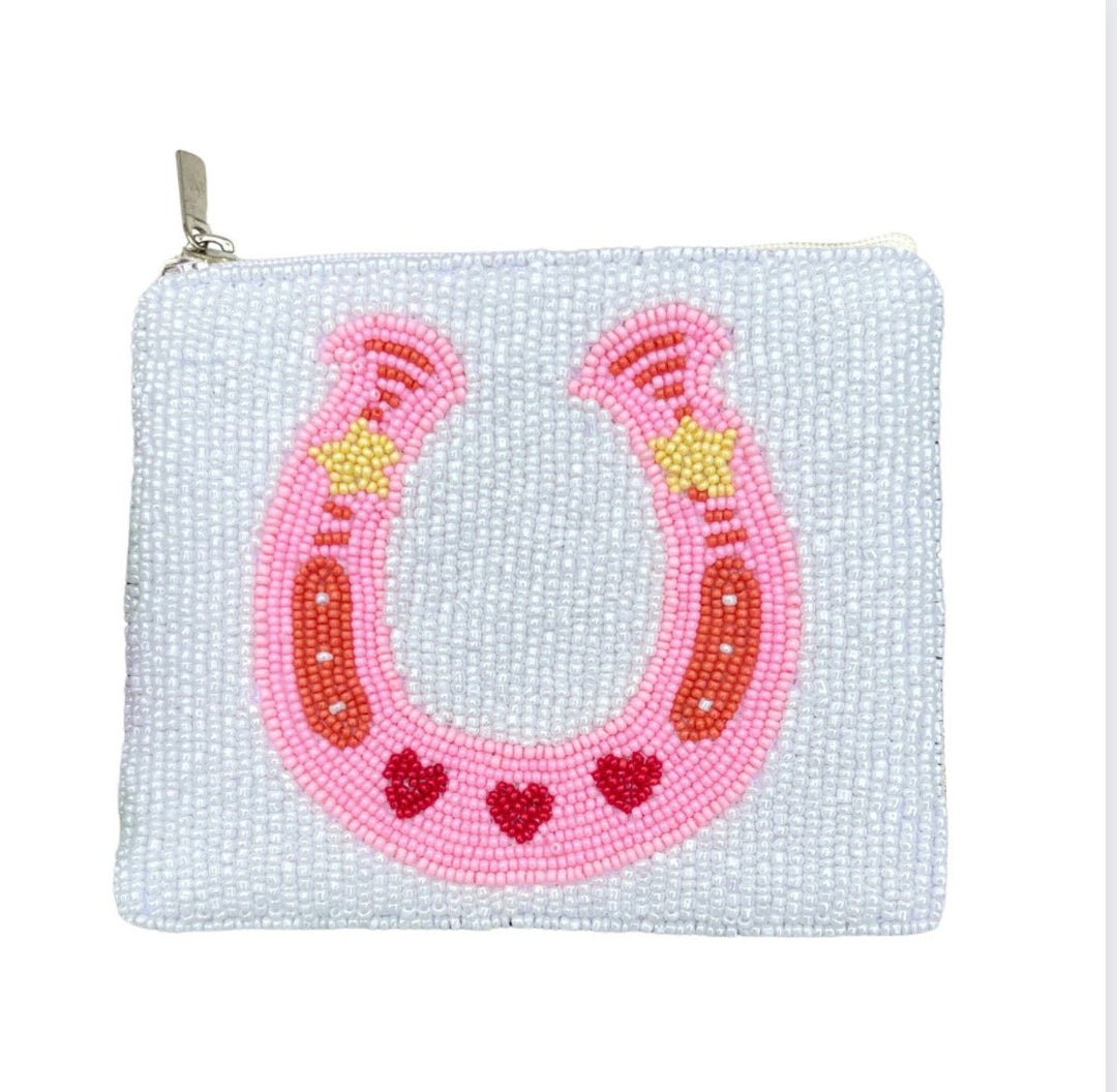 A pink beaded coin purse in the shape of a horseshoe with a zipper closure and a canvas backing.