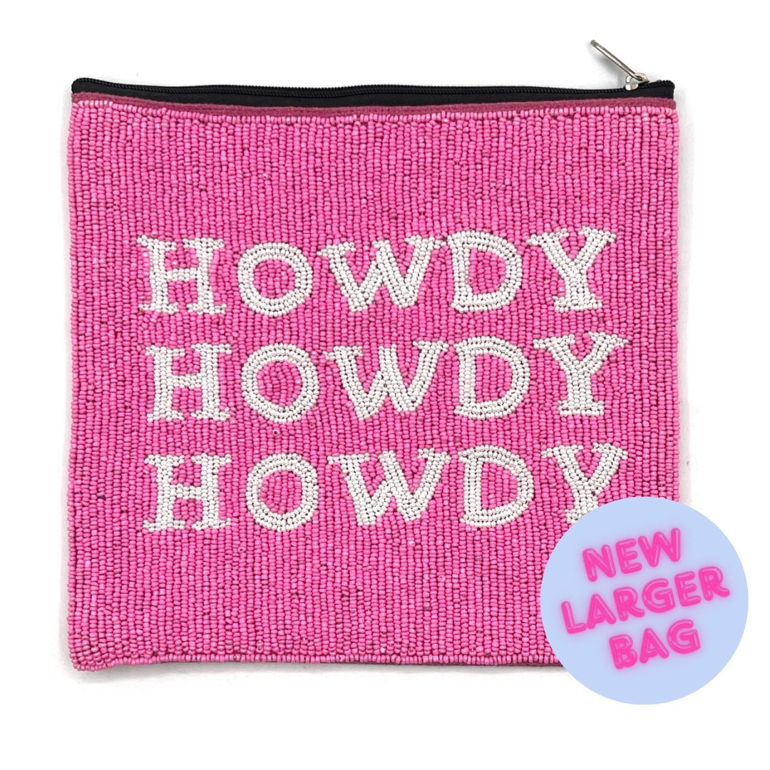 A pink beaded travel bag with the word 'HOWDY' embroidered in large letters, featuring a zipper closure and a canvas backing.