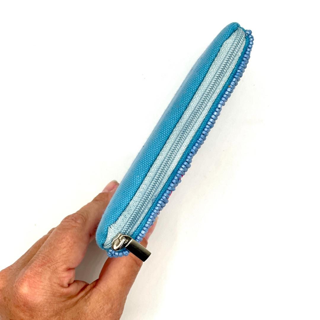 Hand holding a blue zipper pouch against a white background