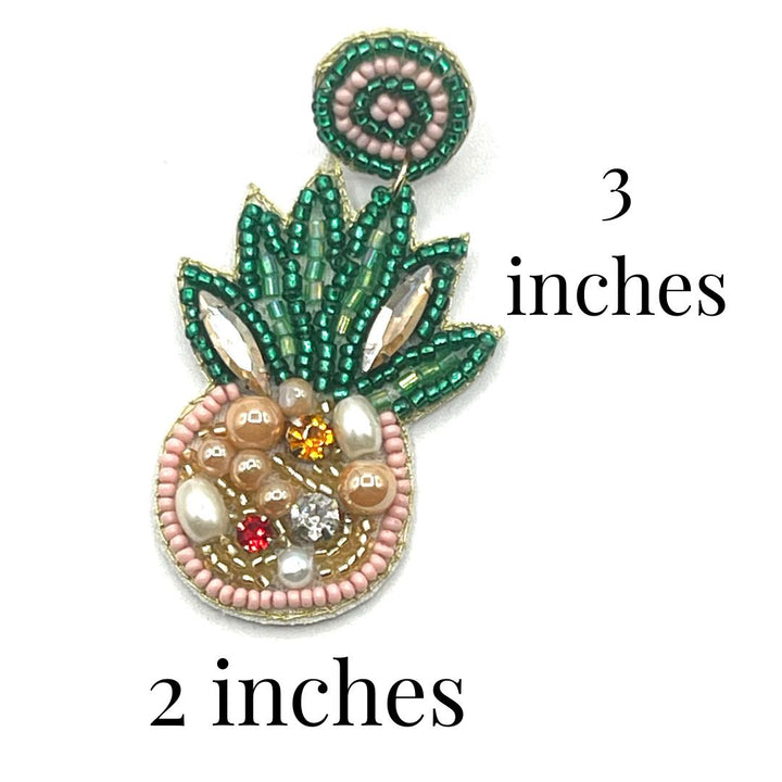 Decorative brooch with green and pink elements on a white background