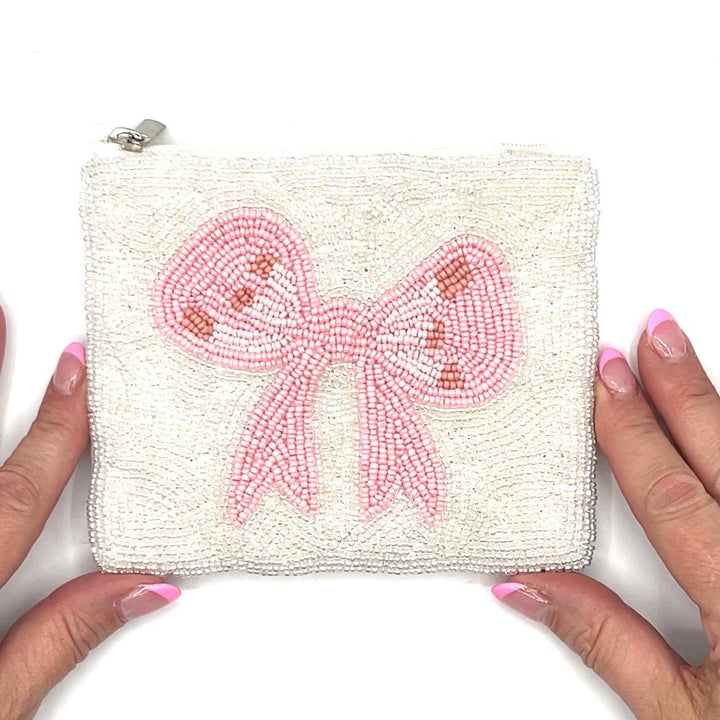 Small pouch with a pink bow design held by hands on a white background