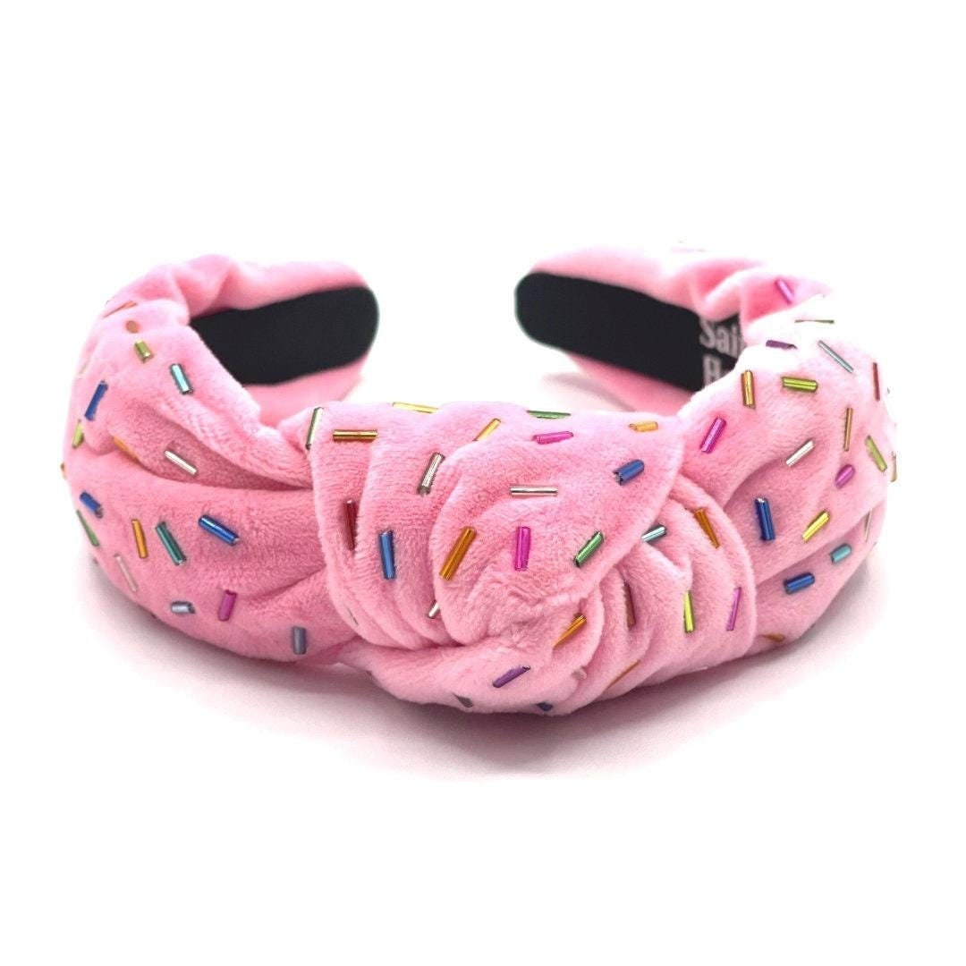 Pink plush headband with colorful sprinkles on a white background