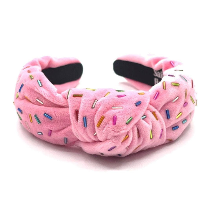 Pink plush headband with colorful sprinkles on a white background