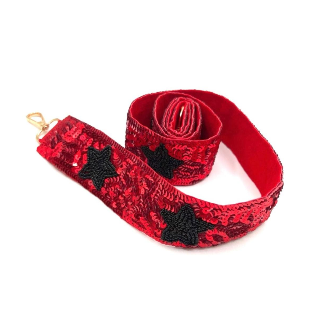 Red sequin guitar strap with black stars on a white background