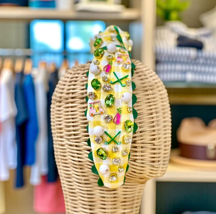 Decorative corn on a stick with colorful embellishments on a wicker stand in a store setting.